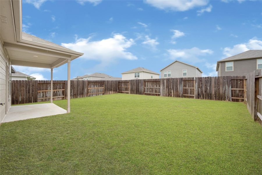 Beautifully landscaped backyard view featuring a pristine green lawn and a fully fenced perimeter.