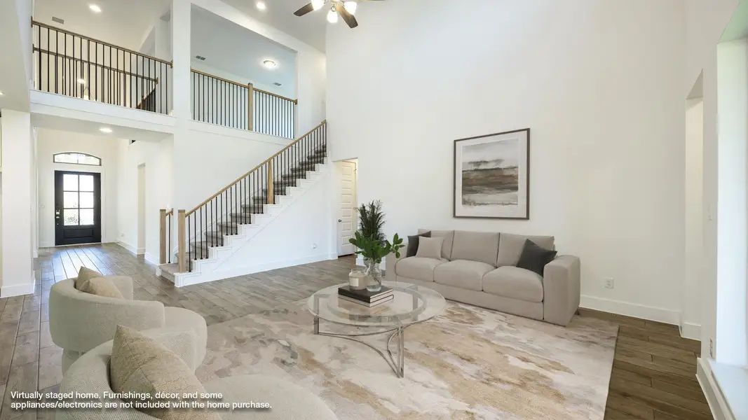 Living room featuring wood finished floors, a towering ceiling, stairs, a ceiling fan, and recessed lighting Living room featuring wood finished floors, a towering ceiling, stairs, a ceiling fan, and recessed lighting