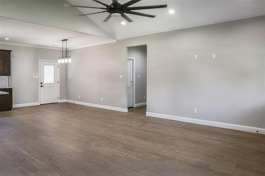 Unfurnished living room featuring crown molding, wood flooring, and ceiling fan