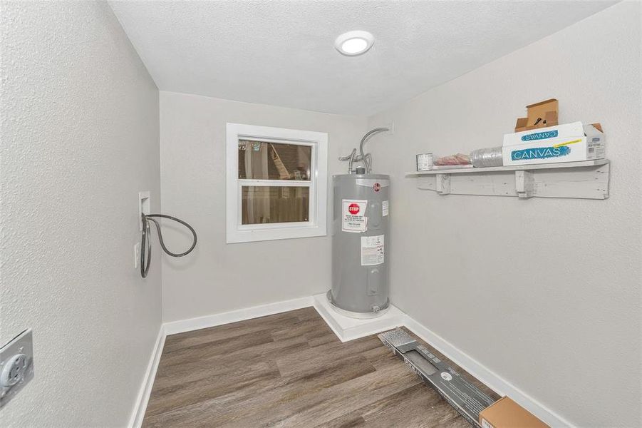 Laundry room featuring water heater and wood finished floors Laundry room featuring water heater and wood finished floors