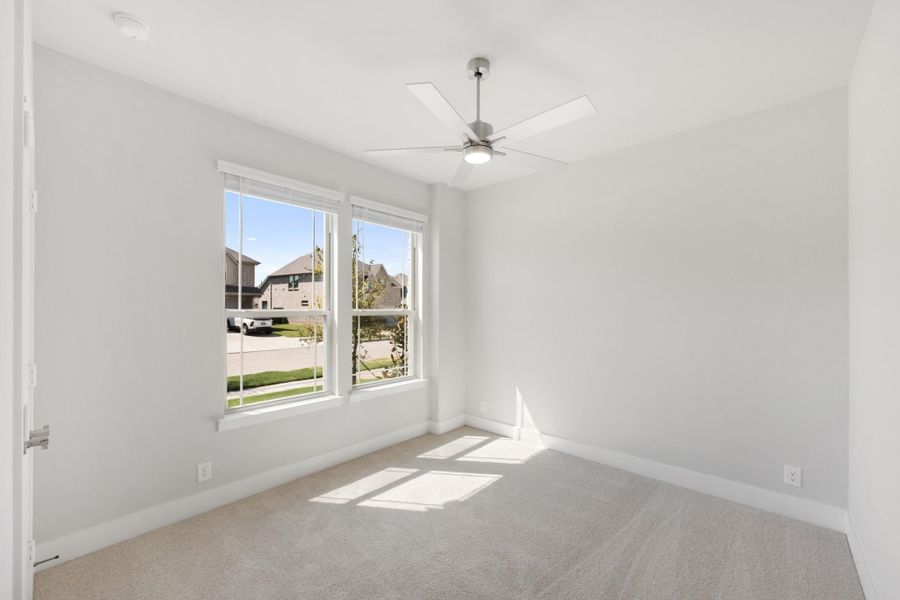 Empty bedroom with carpet flooring, ceiling fan, and two windows with neighborhood view Empty bedroom with carpet flooring, ceiling fan, and two windows with neighborhood view