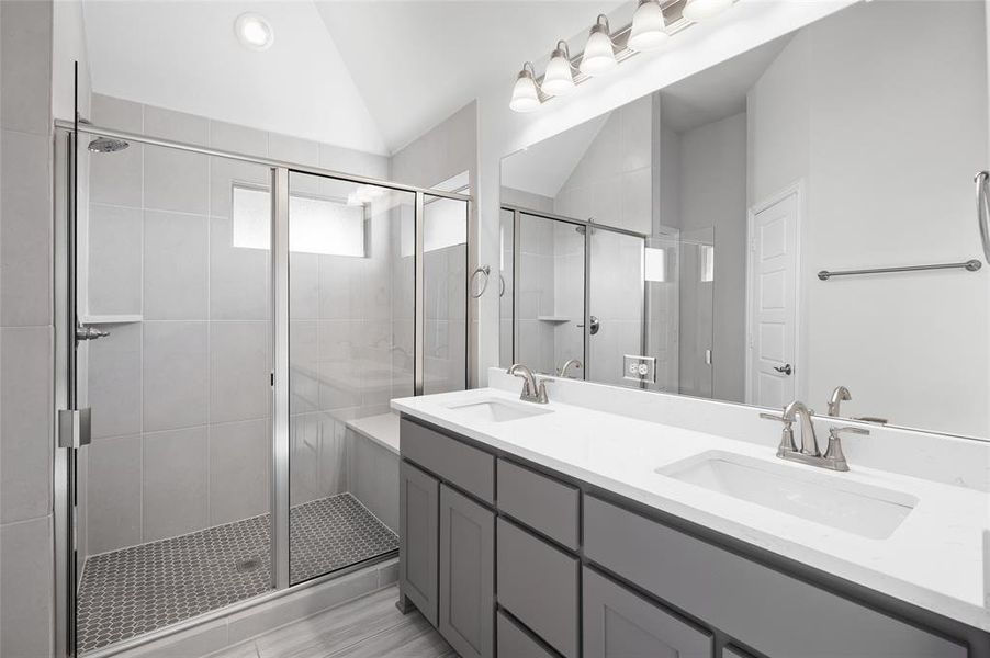 Bathroom featuring lofted ceiling, double vanity, and a stall shower