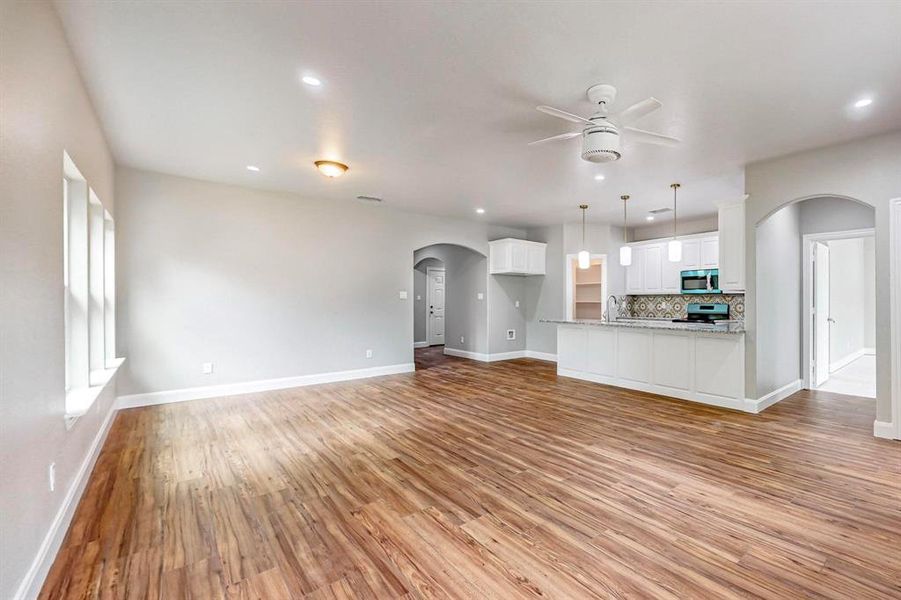 Unfurnished living room with ceiling fan and light wood-type flooring