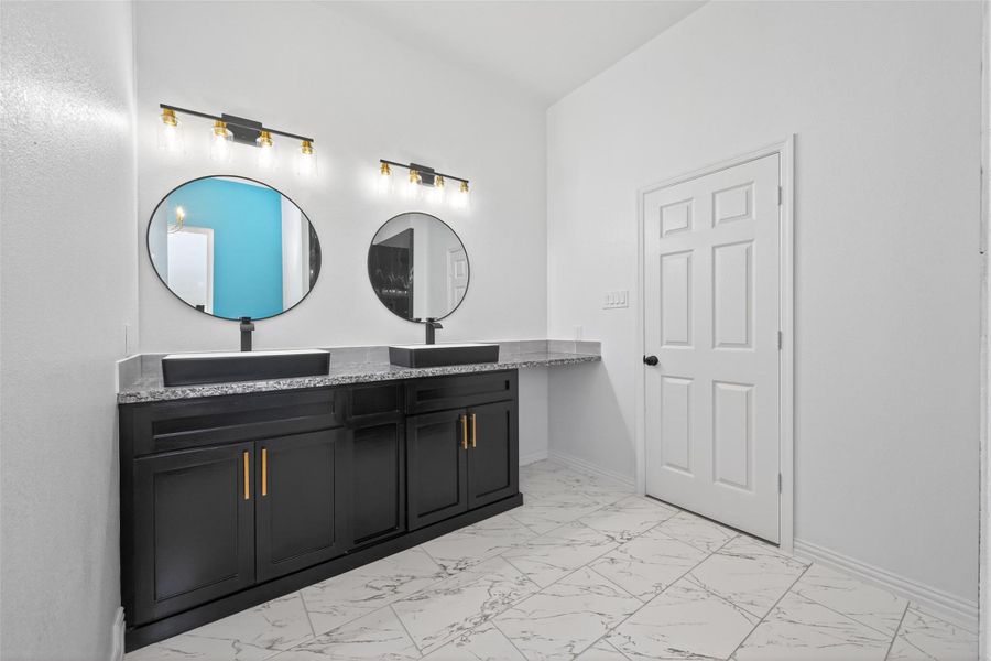 Elegant primary bathroom with dual sinks, custom cabinetry, a freestanding soaking tub, and walk-in shower.