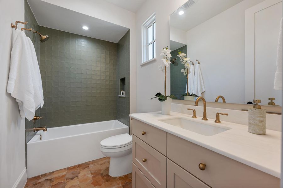 Warm terracotta tiles anchor this bathroom featuring a modern tub and stone counters.