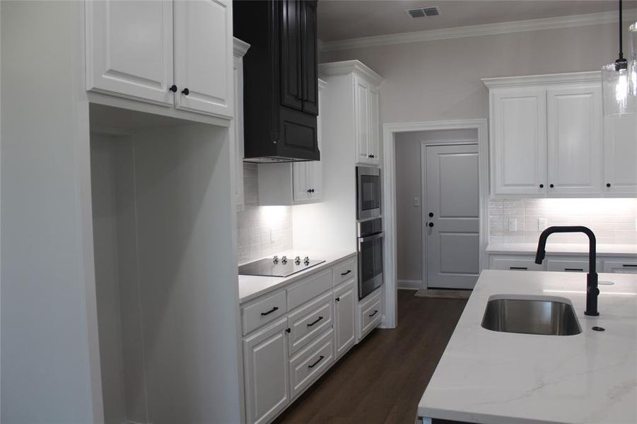 Kitchen featuring a sink, appliances with stainless steel finishes, tasteful backsplash, white cabinets, and crown molding Kitchen featuring a sink, appliances with stainless steel finishes, tasteful backsplash, white cabinets, and crown molding