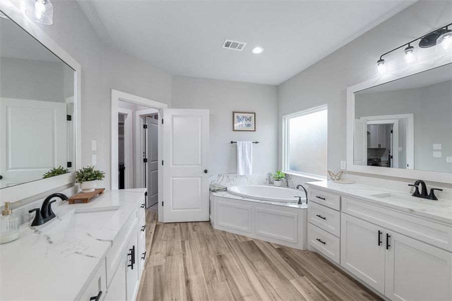 Bathroom featuring hardwood / wood-style flooring, vanity, and a tub