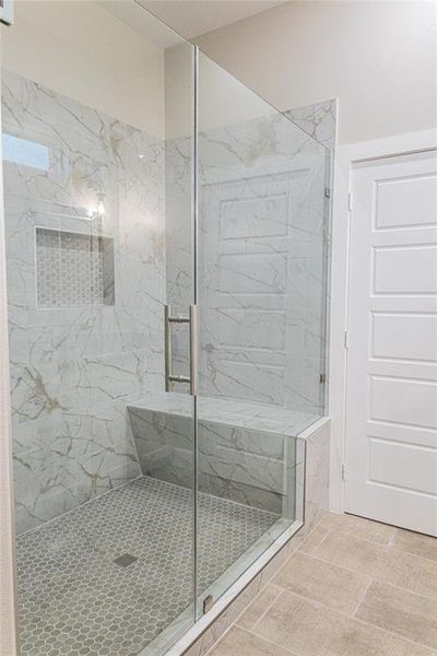 Bathroom featuring a marble finish shower and light tile patterned flooring Bathroom featuring a marble finish shower and light tile patterned flooring