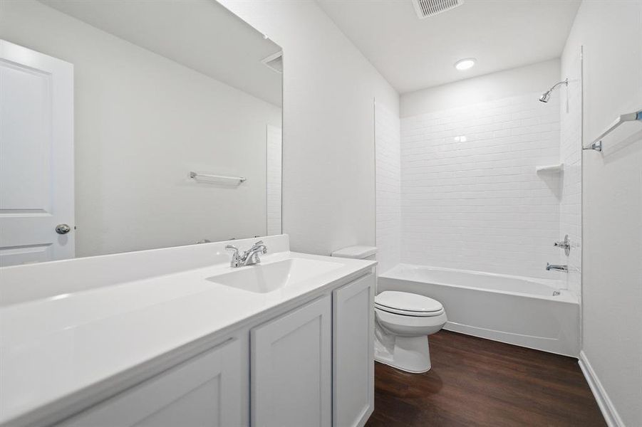 Bathroom featuring a white vanity with integrated sink, chrome faucet, and expansive wall mirror