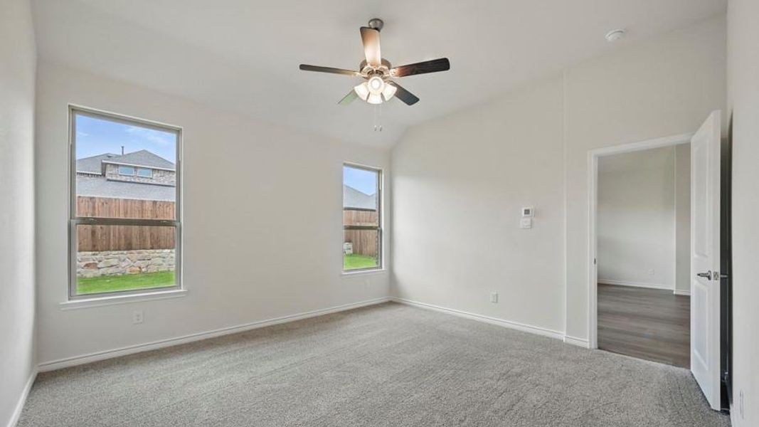 Spacious room featuring vaulted ceilings, light gray carpeting, and two large windows