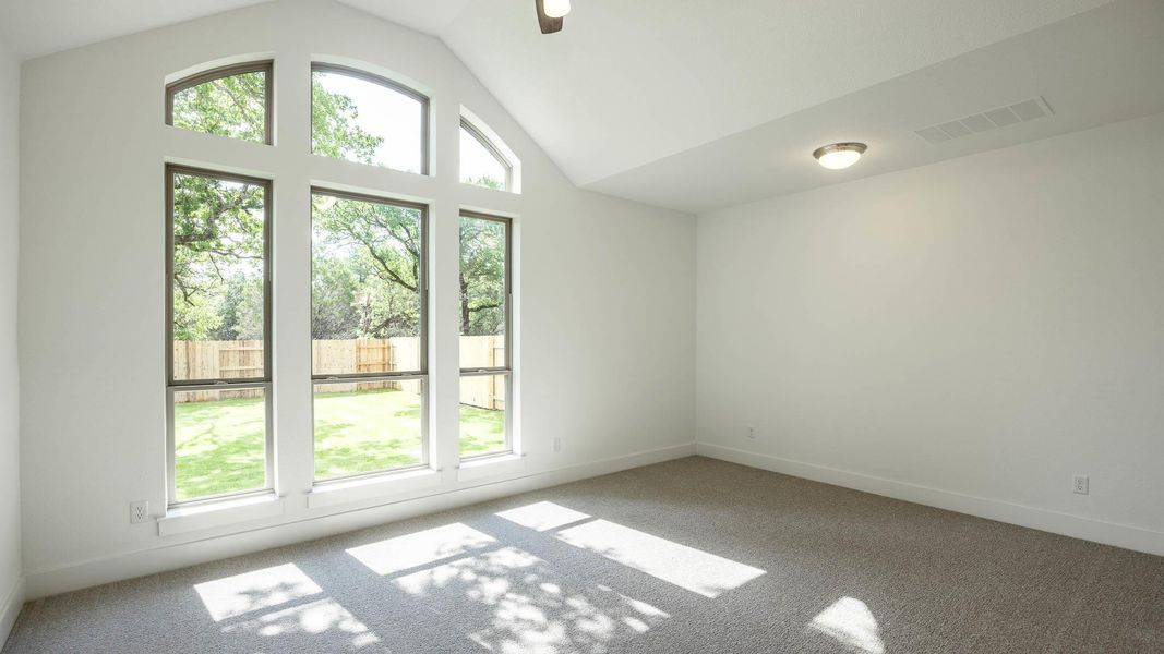 Carpeted empty room featuring vaulted ceiling, baseboards, and ceiling fan Carpeted empty room featuring vaulted ceiling, baseboards, and ceiling fan
