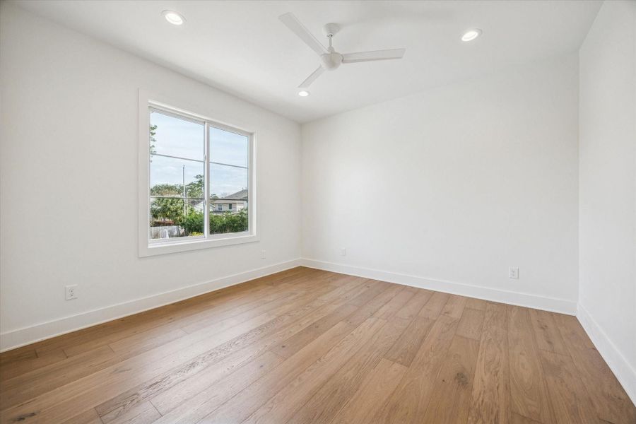 Well proportioned upstairs bedroom offers wide plank hardwood floors, recessed lighting, and a large window that brings in soft natural light. Neutral finishes create a versatile space ready to adapt as a guest room, nursery, or private study.