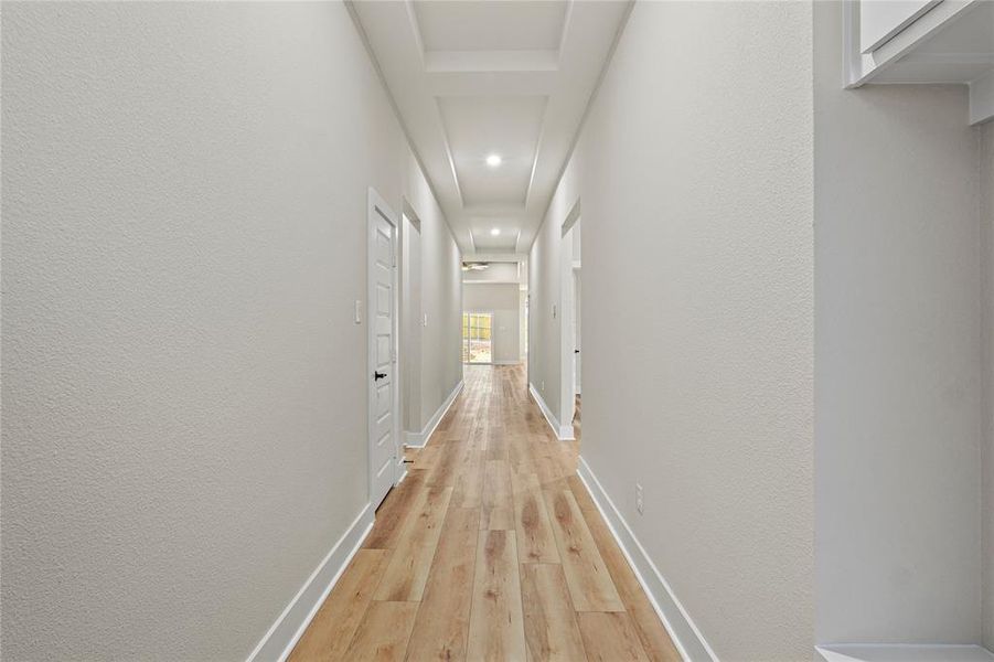 Hall featuring light wood-style floors, recessed lighting, and a textured wall