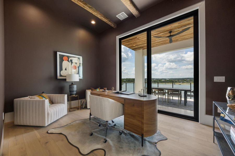 An inviting study with exposed beams offers a stunning waterfront view from its expansive sliding glass doors. An inviting study with exposed beams offers a stunning waterfront view from its expansive sliding glass doors.