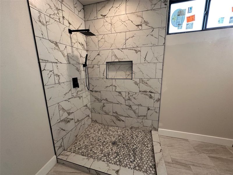 Bathroom with a marble finish shower and light marble finish floors