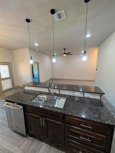 Kitchen island with dark wood cabinetry, a stainless steel sink, and a high-arch faucet Kitchen island with dark wood cabinetry, a stainless steel sink, and a high-arch faucet