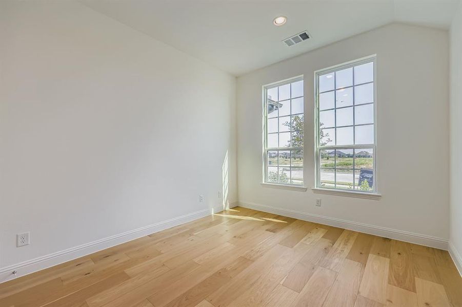 Empty room featuring light wood finished floors, recessed lighting, and vaulted ceiling