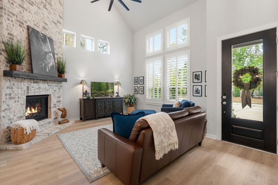 Abundance of windows brings in natural light for the living area and throughout the home - notice the floor to ceiling brick fireplace - and window shutters.