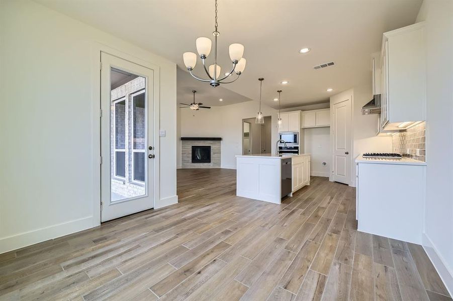 Kitchen featuring range hood, visible vents, stainless steel appliances, white cabinetry, and open floor plan