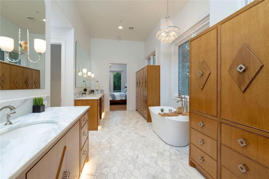 Bathroom featuring a chandelier, a soaking tub, ensuite bath, and two vanities Bathroom featuring a chandelier, a soaking tub, ensuite bath, and two vanities