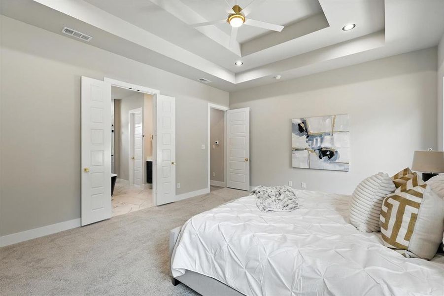 Bedroom featuring light colored carpet, a raised ceiling, recessed lighting, and a ceiling fan