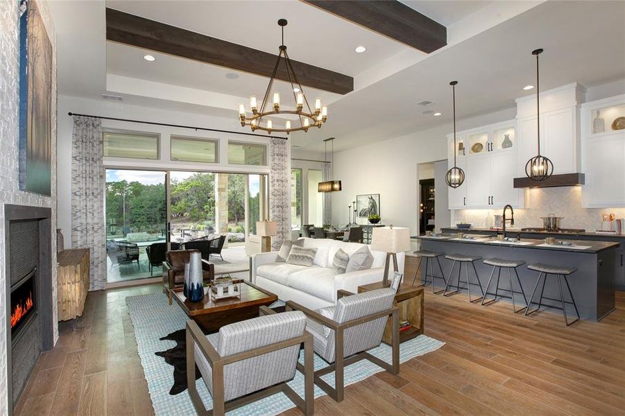 Living room featuring beamed ceiling, a tiled fireplace, light wood-type flooring, and an inviting chandelier