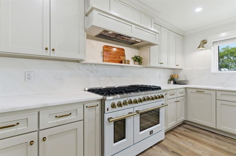 The kitchen features white cabinetry with gold-toned hardware, white countertops, and a white range with gold-toned accents The kitchen features white cabinetry with gold-toned hardware, white countertops, and a white range with gold-toned accents