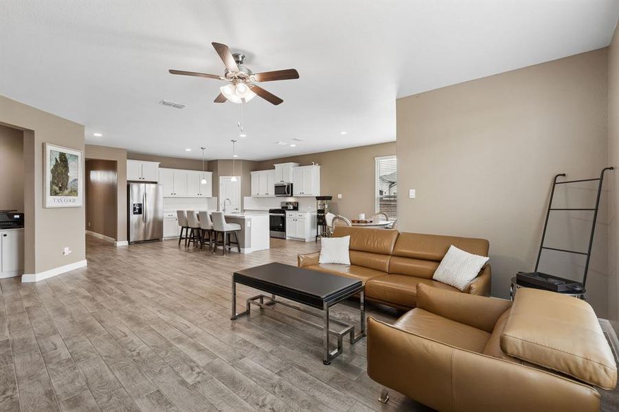 Open-concept living area with wood-finish flooring, a contemporary ceiling fan, and recessed lighting