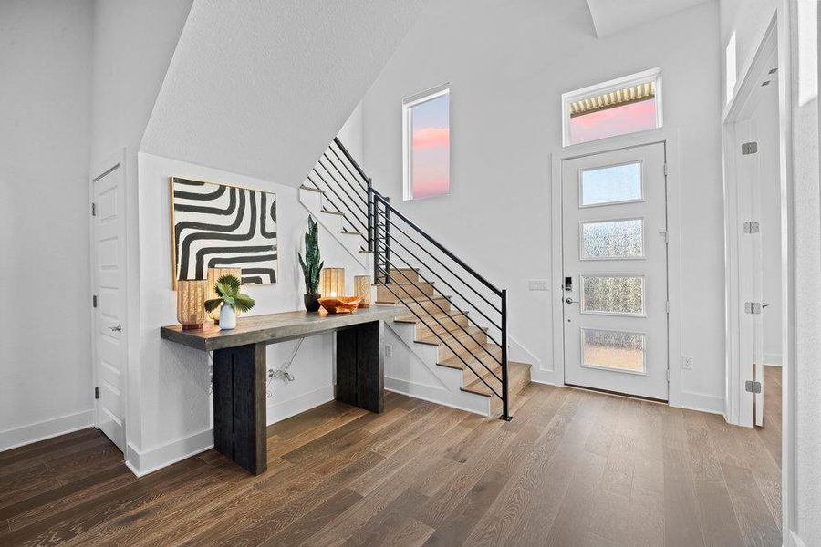 Entrance foyer with dark wood-type flooring, stairway, and high vaulted ceiling