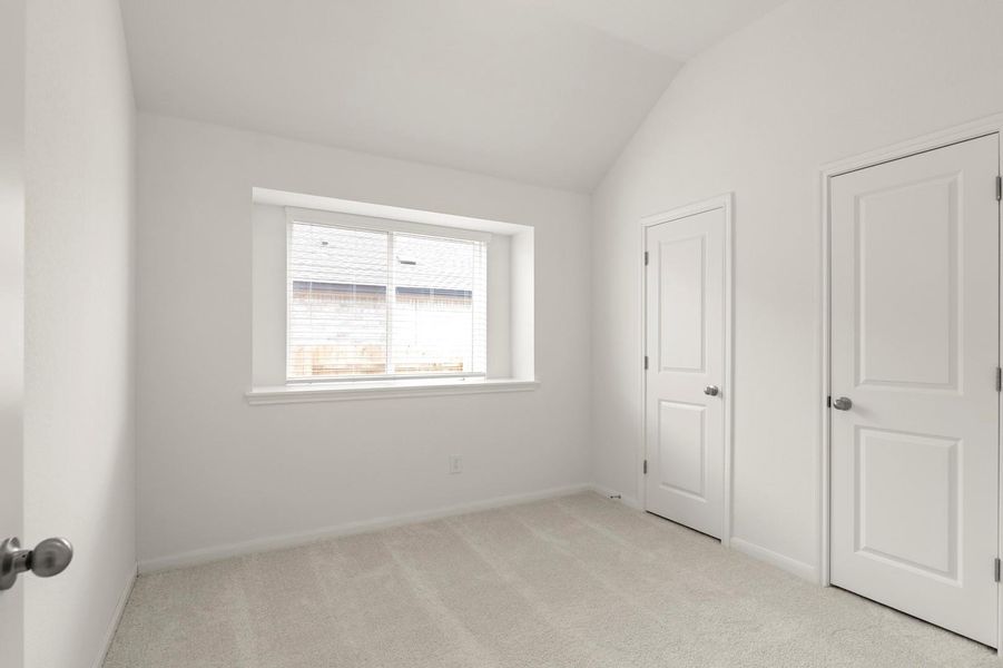 Unfurnished bedroom with light carpet and vaulted ceiling