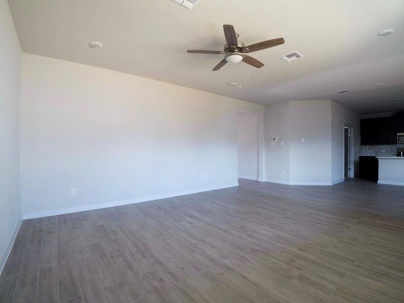 Unfurnished living room featuring dark wood-style floors and ceiling fan Unfurnished living room featuring dark wood-style floors and ceiling fan