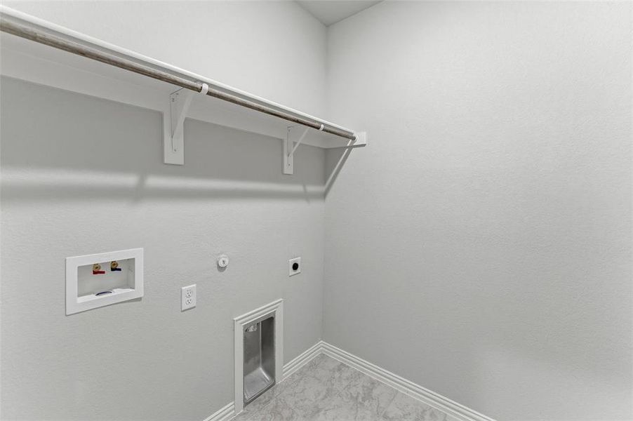 Dedicated laundry space featuring a built-in shelf, hanging rod, and base trim Dedicated laundry space featuring a built-in shelf, hanging rod, and base trim