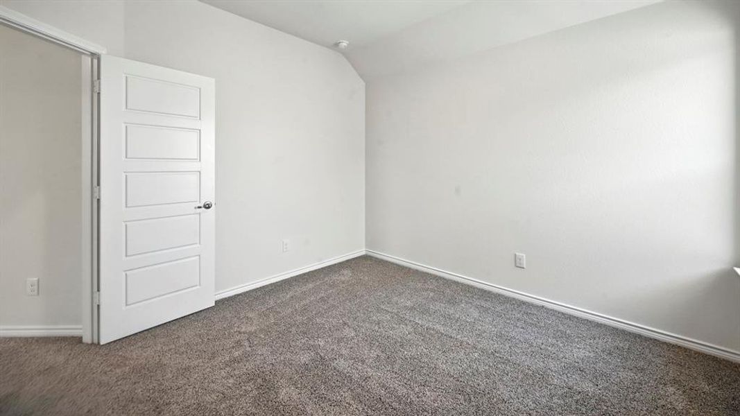 Unfurnished room with lofted ceiling and dark colored carpet