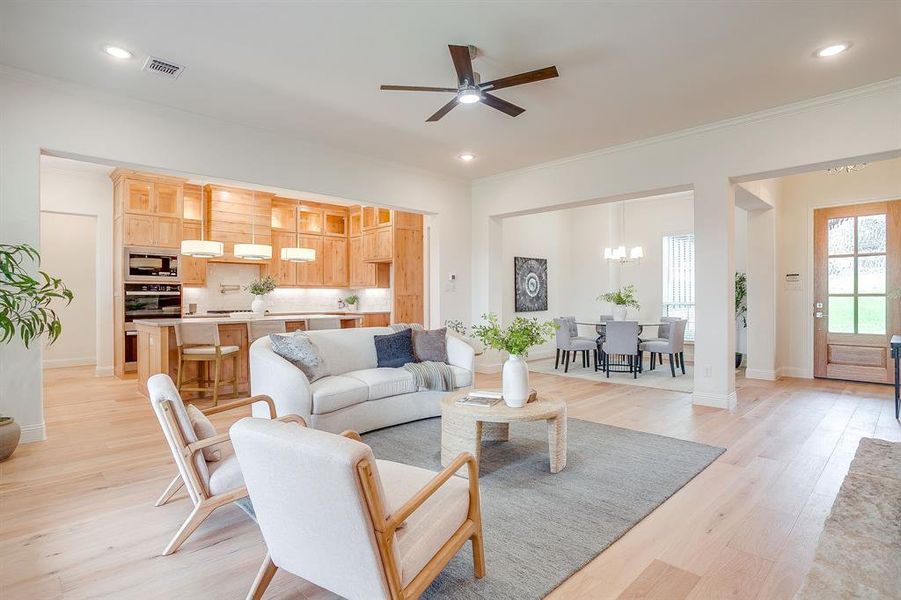 Living area with built in adjustable shelves, light engineered wood flooring, a stone fireplace with solid cedar mantle, ceiling fan, and french doors that open to a covered back patio.