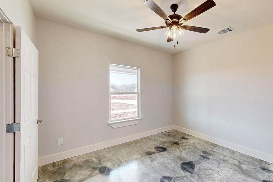 Unfurnished room with concrete flooring, visible vents, ceiling fan, and baseboards