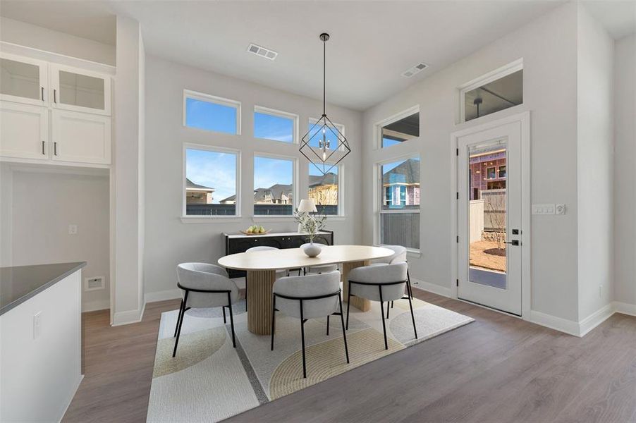 Dining area with light wood finished floors, healthy amount of natural light, and suspended lighting