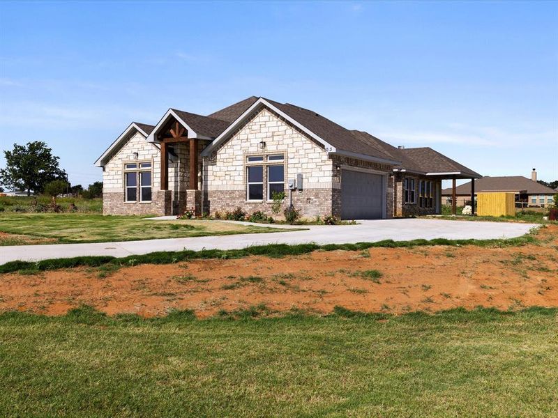 Craftsman house with a garage, stone siding, a front yard, and driveway