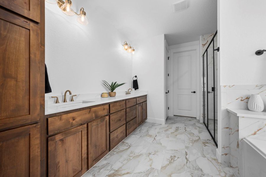 Full bathroom with double vanity, a marble finish shower, and light marble finish floors