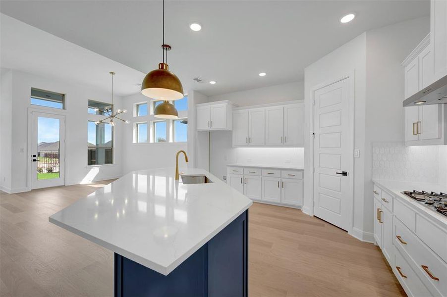 Kitchen featuring a center island with sink, white cabinets, and light wood-style floors