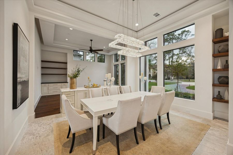 Elegant formal dining room featuring designer lighting, and walls of windows overlooking the grounds. Elegant formal dining room featuring designer lighting, and walls of windows overlooking the grounds.