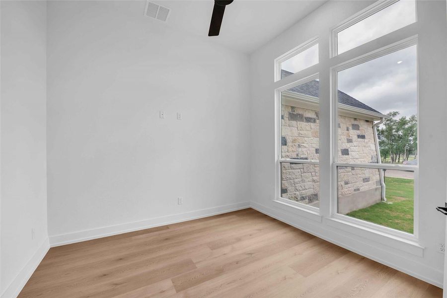 Spare room with visible vents, plenty of natural light, ceiling fan, and light wood-type flooring Spare room with visible vents, plenty of natural light, ceiling fan, and light wood-type flooring