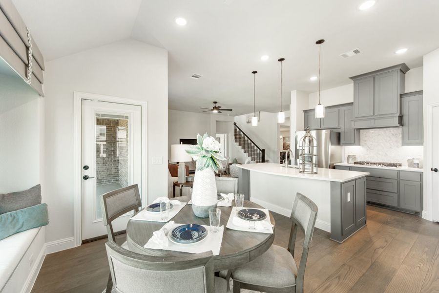 Open-concept dining area with round table and kitchen featuring gray cabinets and white island in background