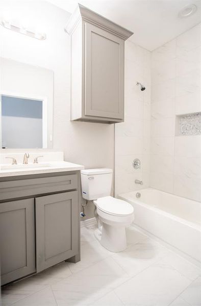 Full bathroom featuring vanity, tile patterned flooring, tiled shower / bath, and toilet