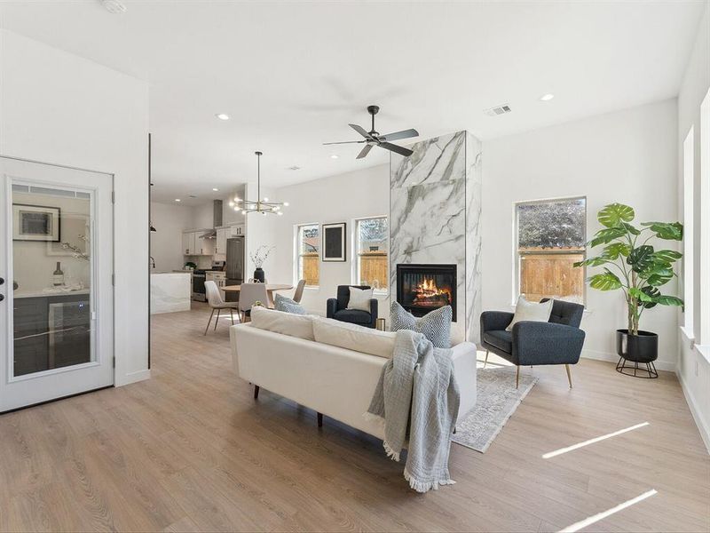 Living room with baseboards, visible vents, light wood-style floors, a fireplace, and recessed lighting