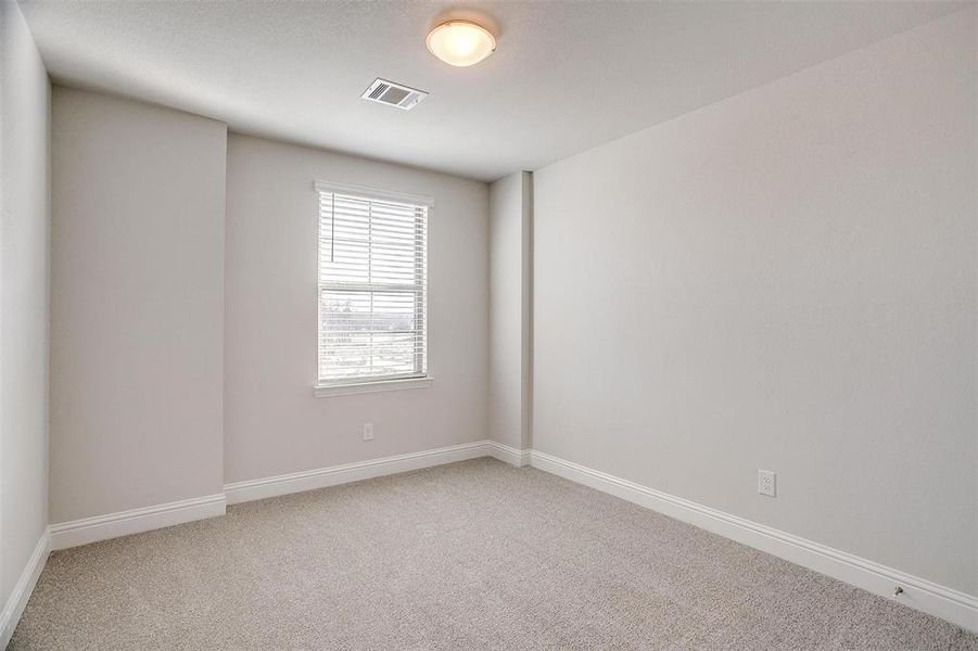 Empty room featuring visible vents, light carpet, and baseboards