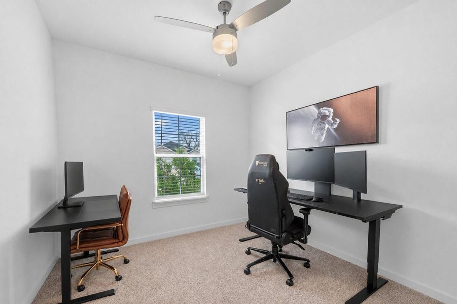 A bedroom converted into a dedicated workspace offers ample room for a large desk and media setup, providing a functional and versatile environment.