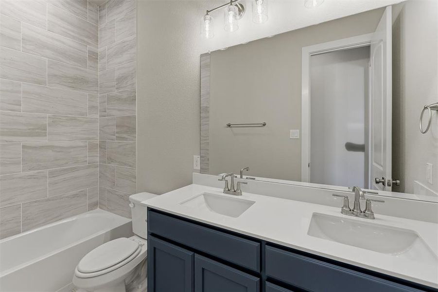 Bathroom featuring a double vanity with white countertops, dual undermount sinks, and a dark blue cabinet base