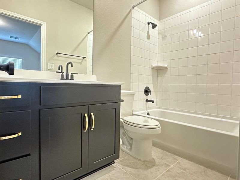 En-suite Full bath with toilet, tile floors, vanity, and washtub / shower combination En-suite Full bath with toilet, tile floors, vanity, and washtub / shower combination