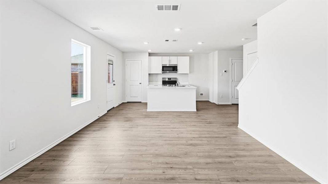 Kitchen featuring white cabinetry, a kitchen island with sink, light countertops, light wood-style floors, and recessed lighting