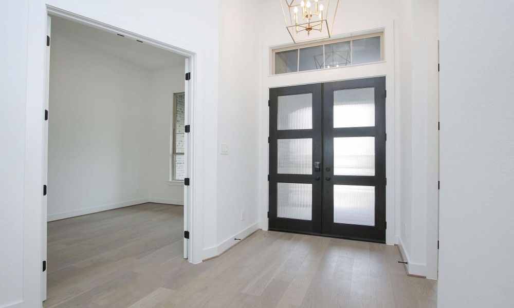 Foyer entrance with a chandelier, light wood-style flooring, and french doors
